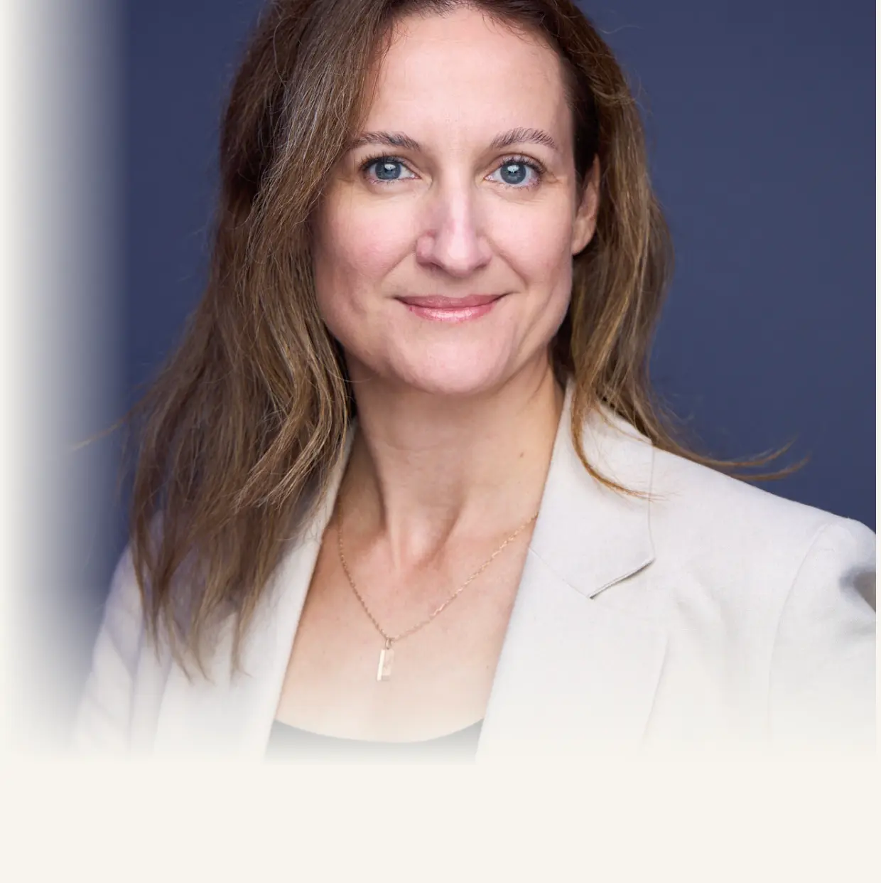 Retrato profesional de una mujer con cabello castaño, ojos azules y una elegante chaqueta blanca.